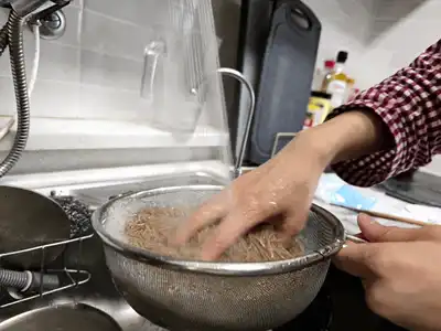 체에 받친 메밀면을 찬물에 헹구는 모습