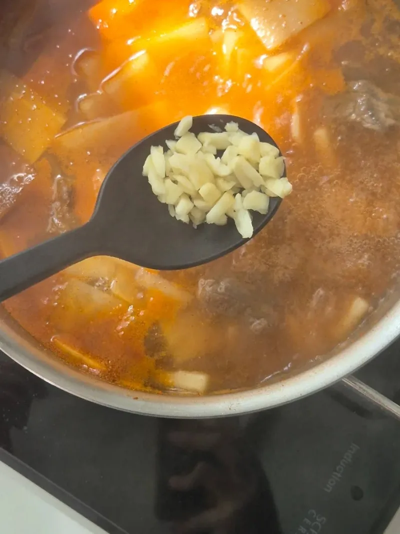 끓는 국에 다진 마늘을 넣는 모습